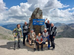 Eine Gruppe Motorradfahrer steht vor dem Col de la Bonnette.