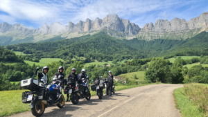 Eine Gruppe Motorradfahrer steht vor dem Bergmassiv des Vercours.